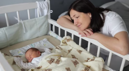 Madre observando con cariño al bebé durmiendo tranquilo en la cuna